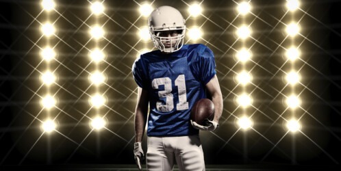 Football,player,with,a,blue,uniform,in,front,of,lights