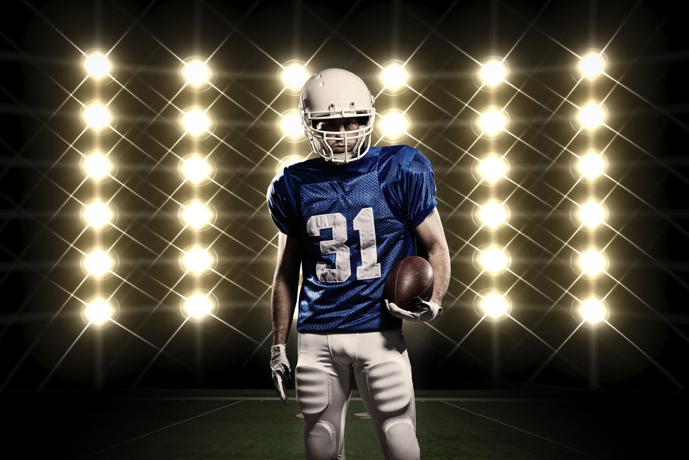 Football,player,with,a,blue,uniform,in,front,of,lights